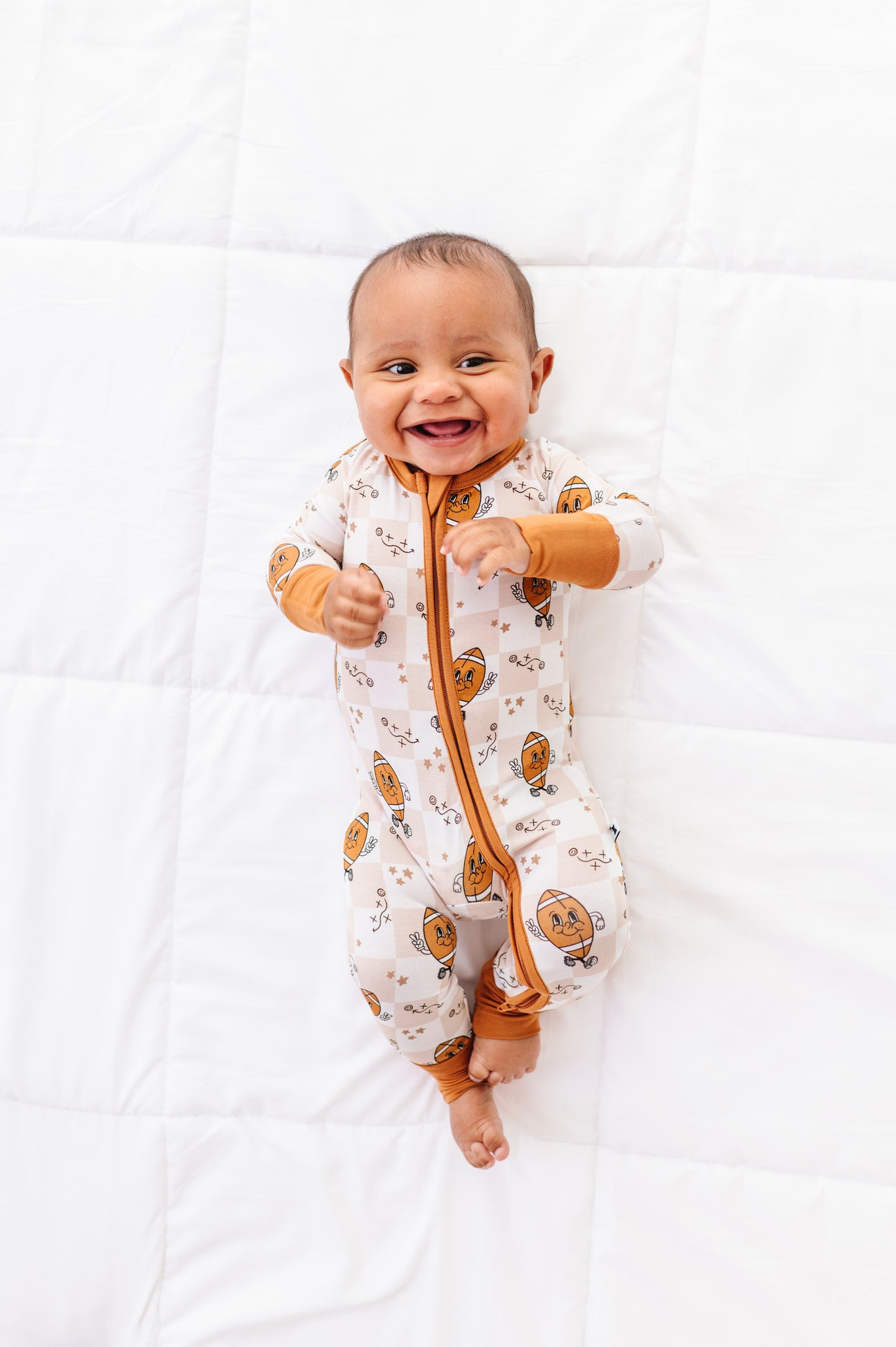 Baby wearing a patterned onesie with orange accents on a white background