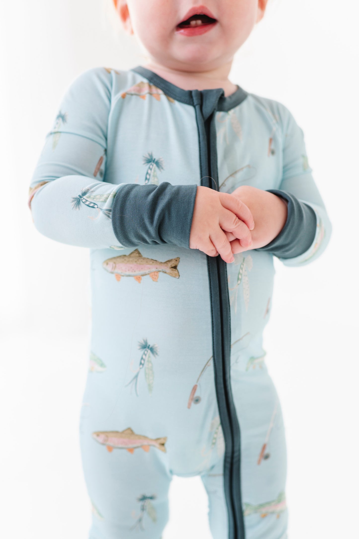 Child wearing a light blue onesie with animal prints on a white background