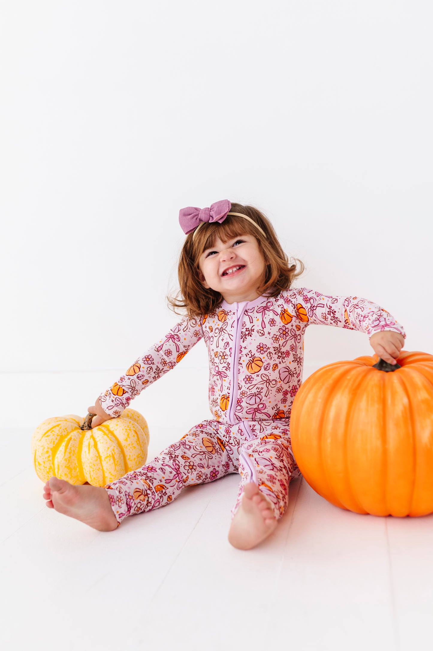 Girl in Purple Pumpkin and Bow Footies by Kiki and Lulu