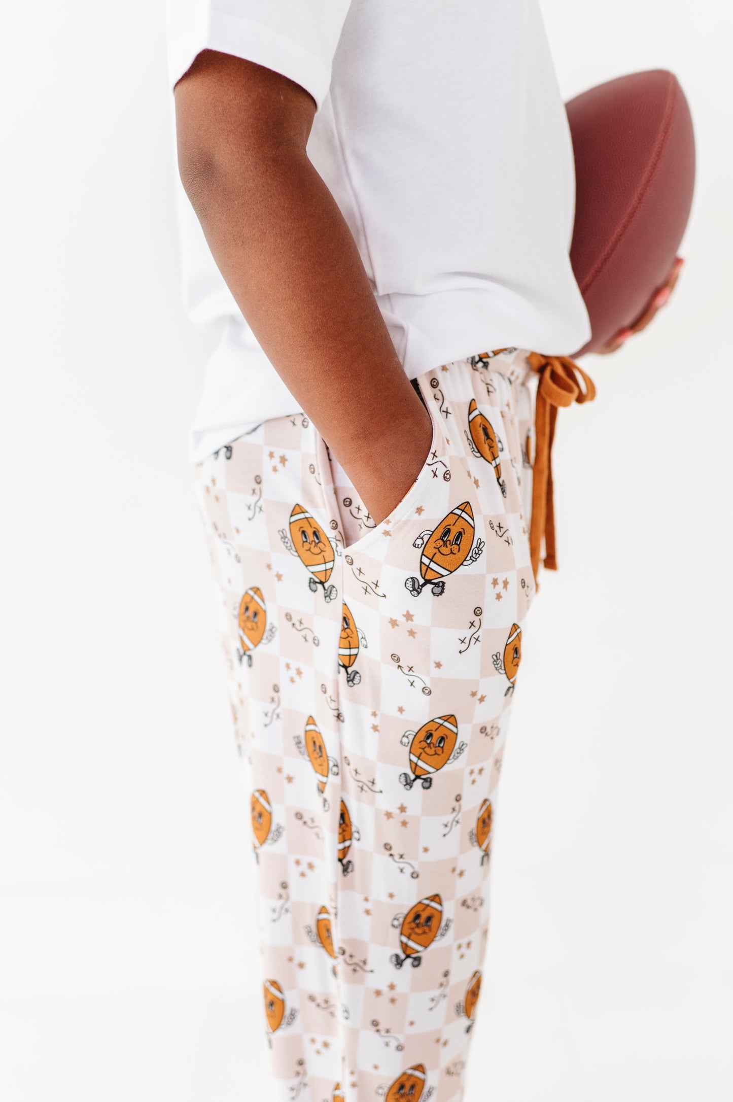 Person wearing white pajama top and pumpkin-patterned pants on a white background