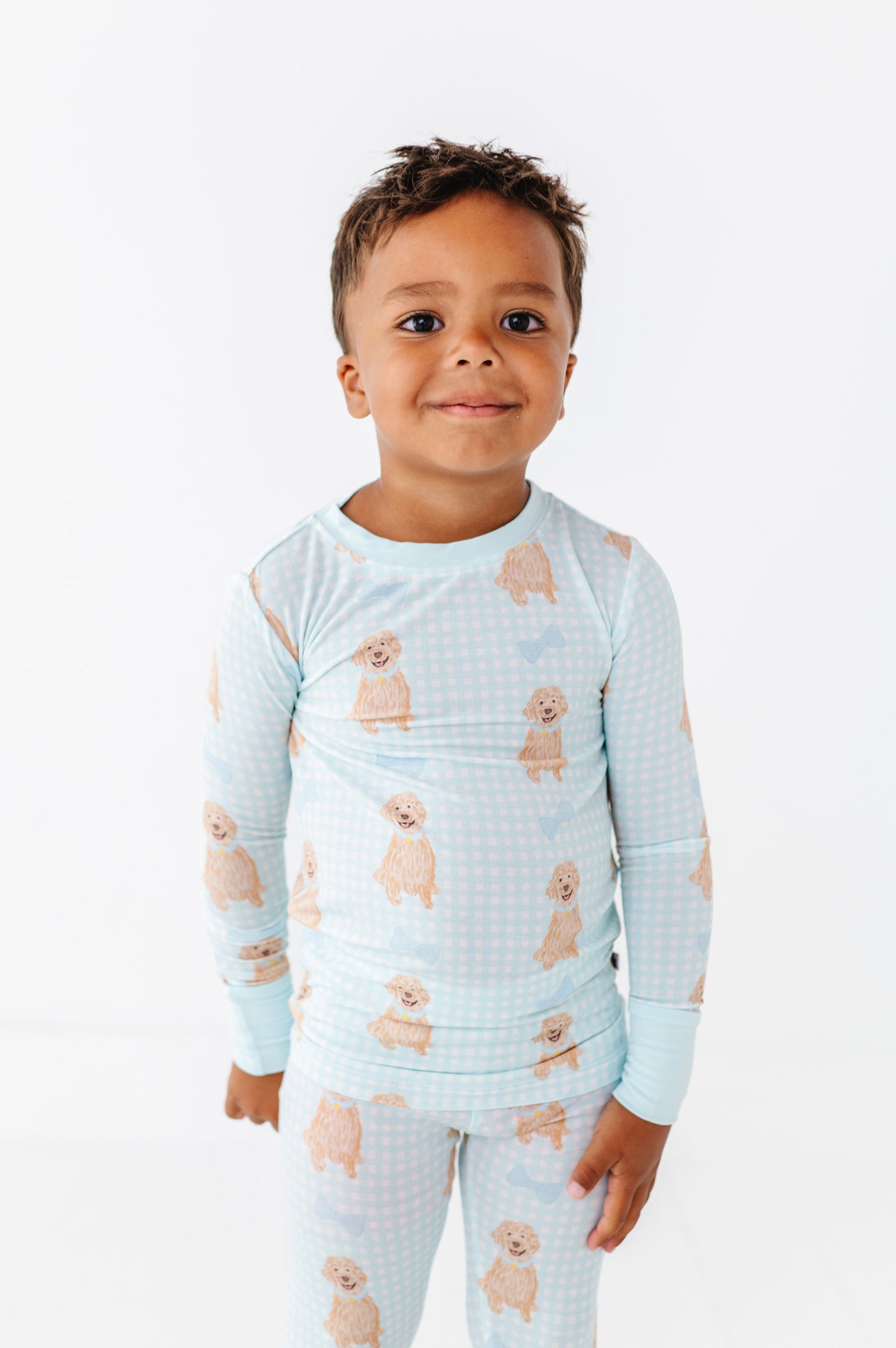 Child wearing a light blue pajama set with dog pattern on a white background