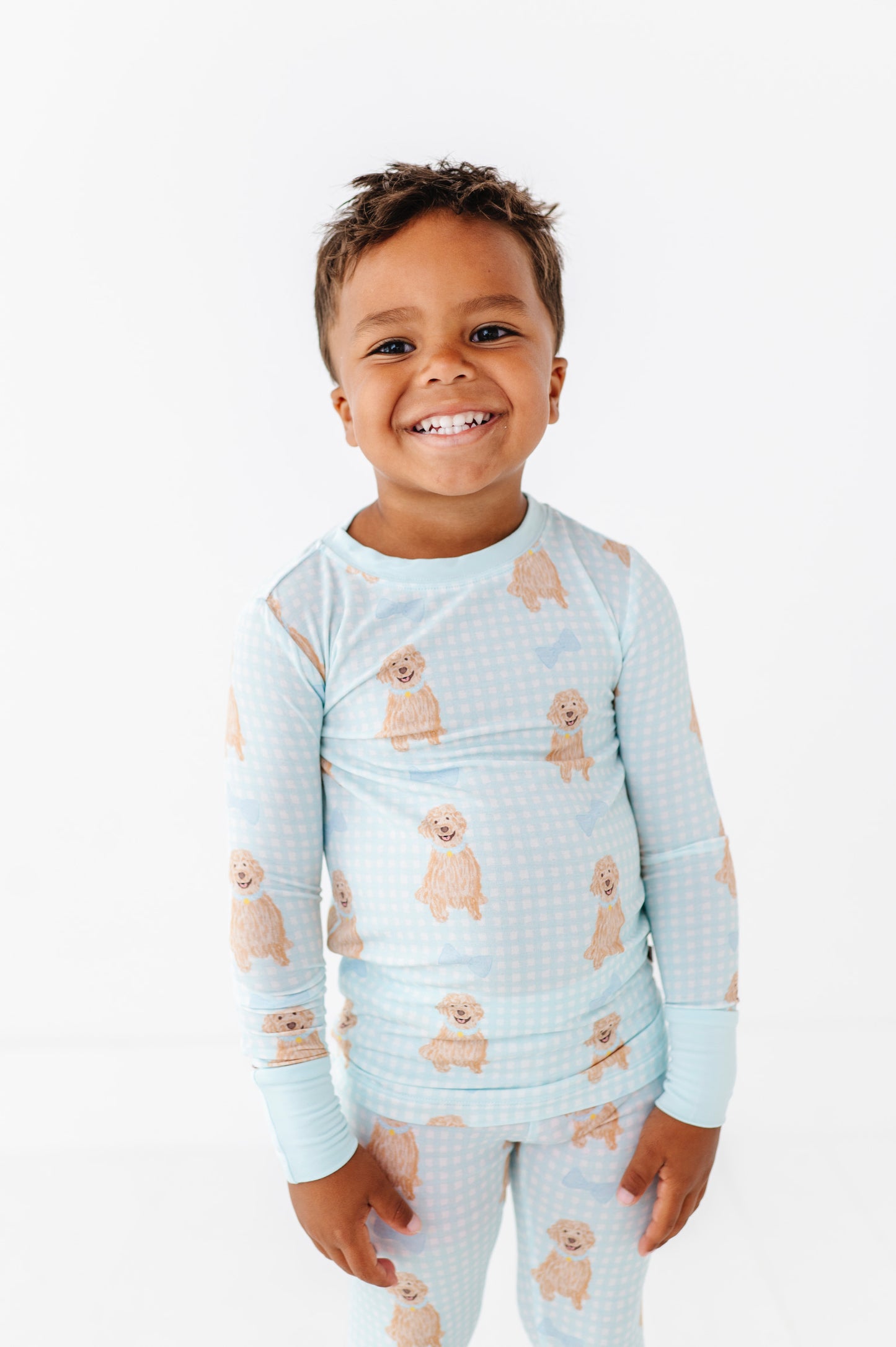 Child wearing a light blue pajama set with dog prints on a white background