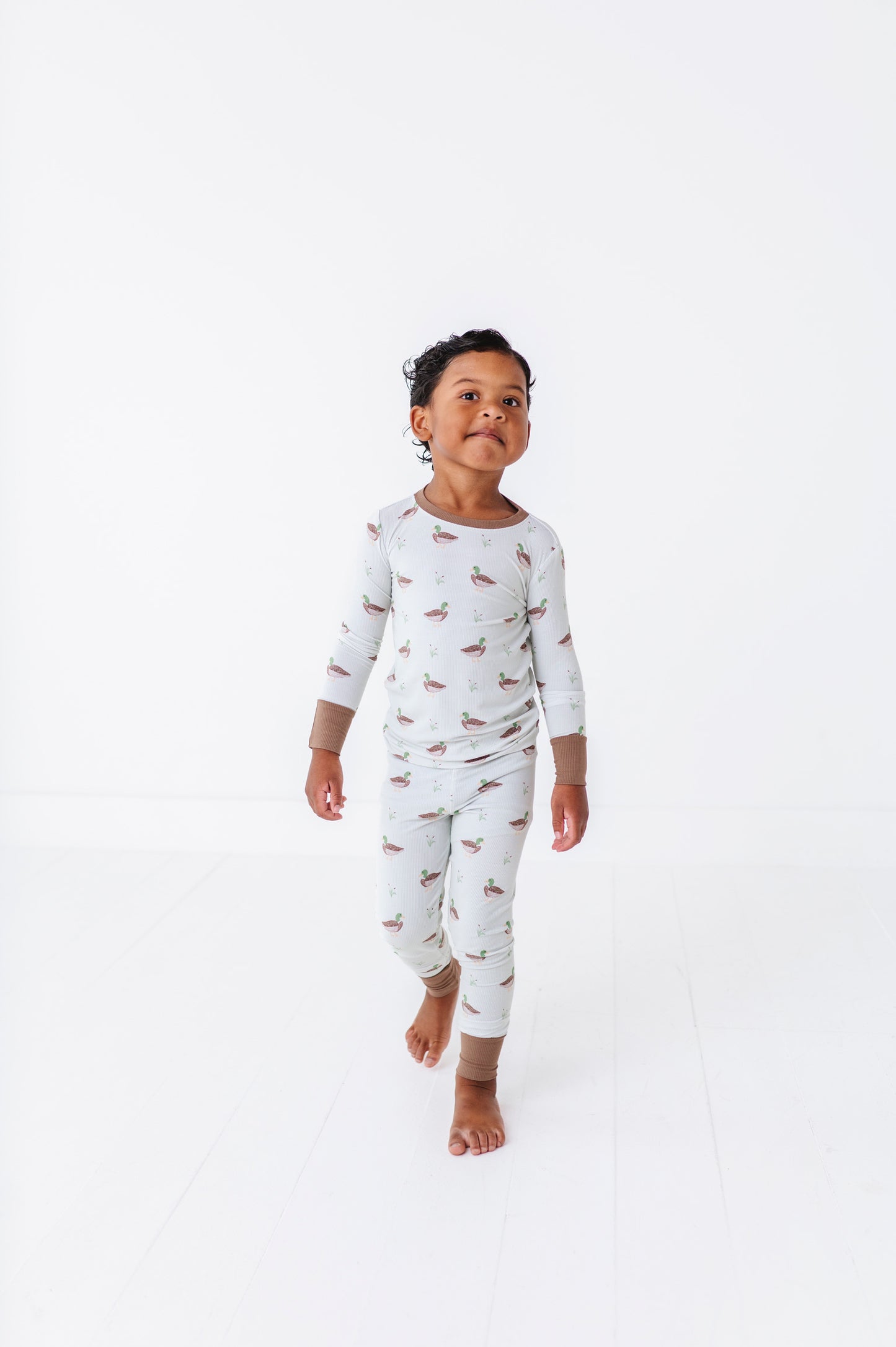Child wearing a white onesie with bird pattern on a white background