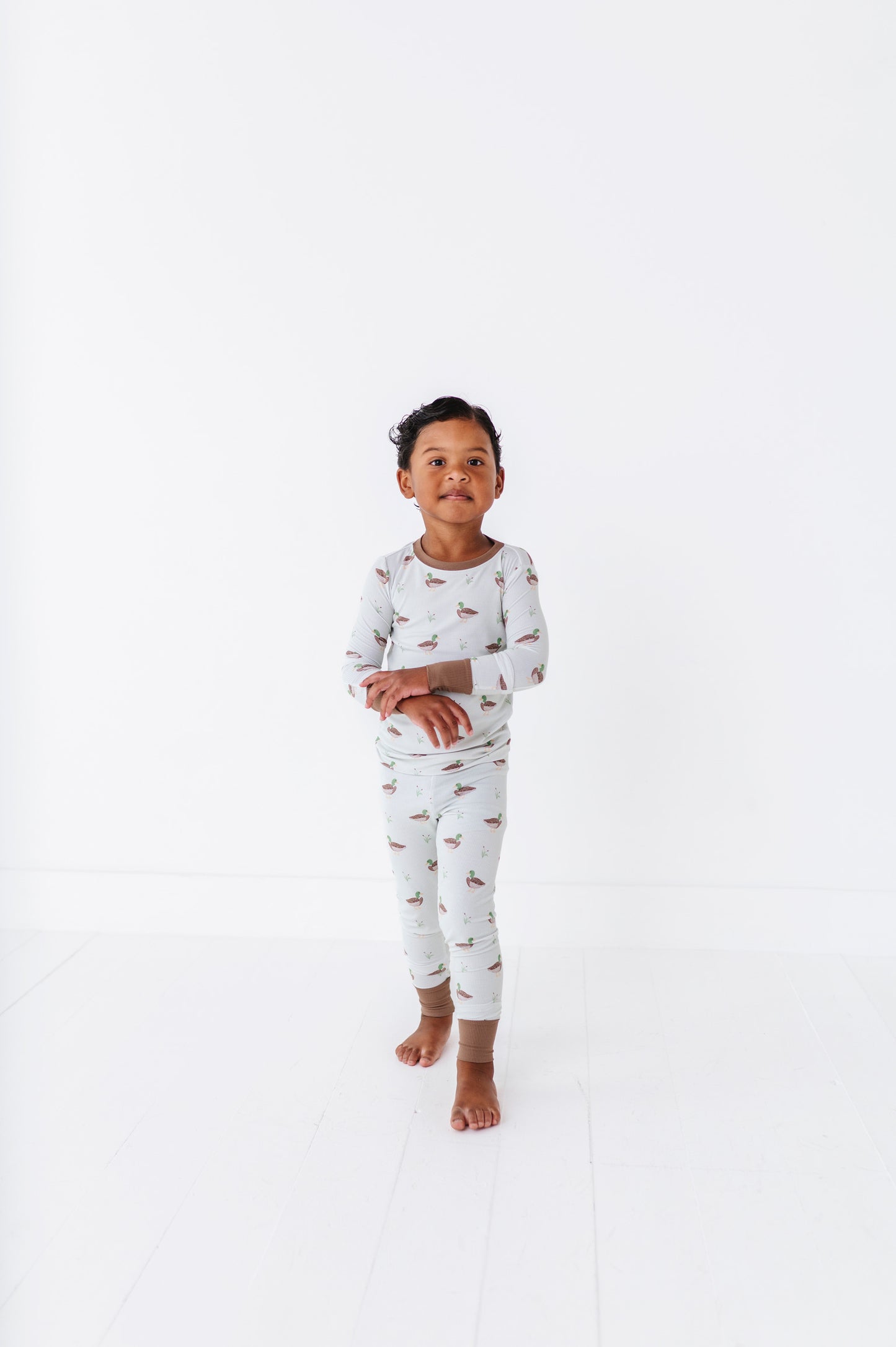 Child wearing a patterned pajama set on a white background