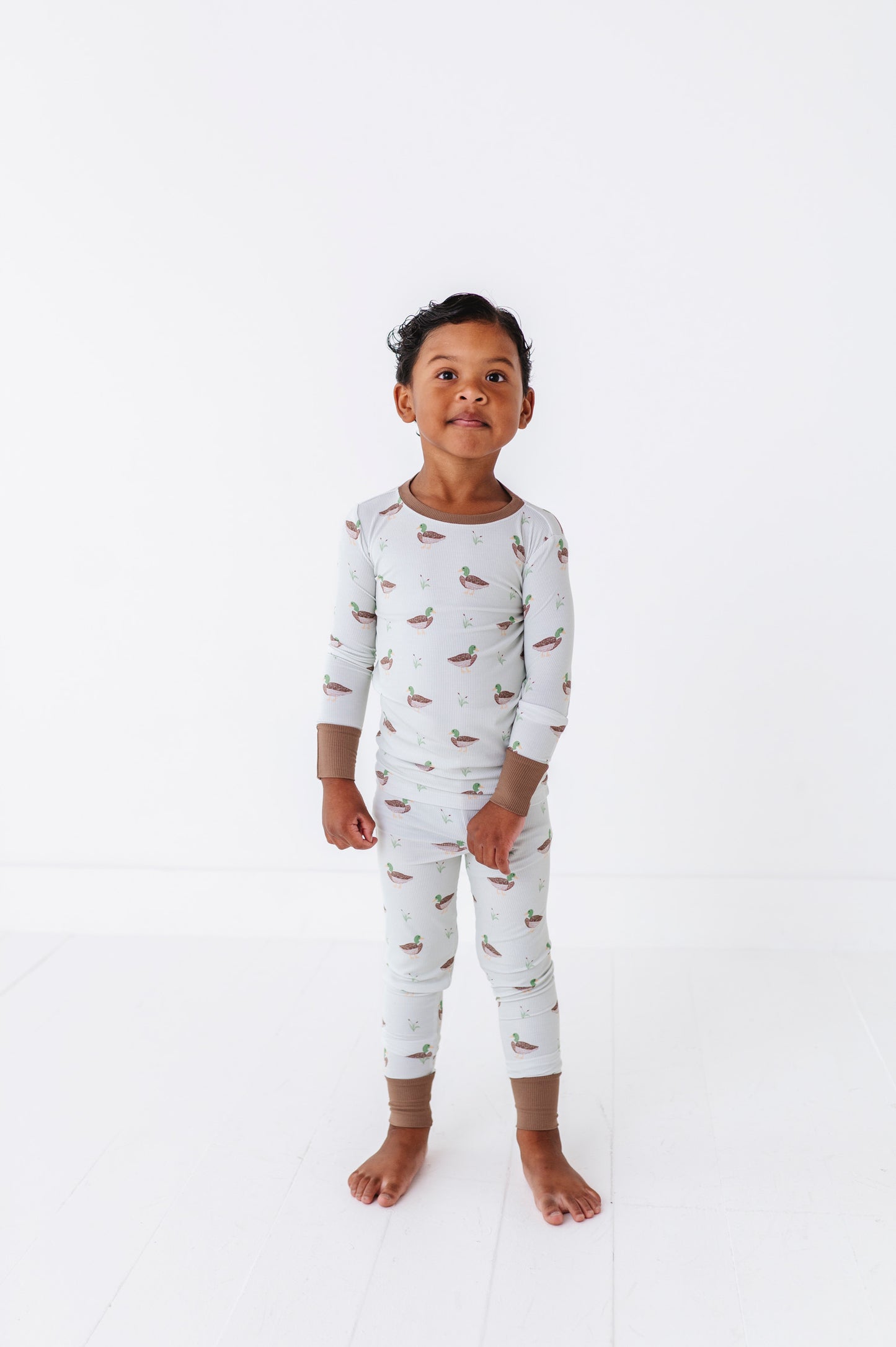 Child wearing a white long-sleeve pajama set with small prints on a white background