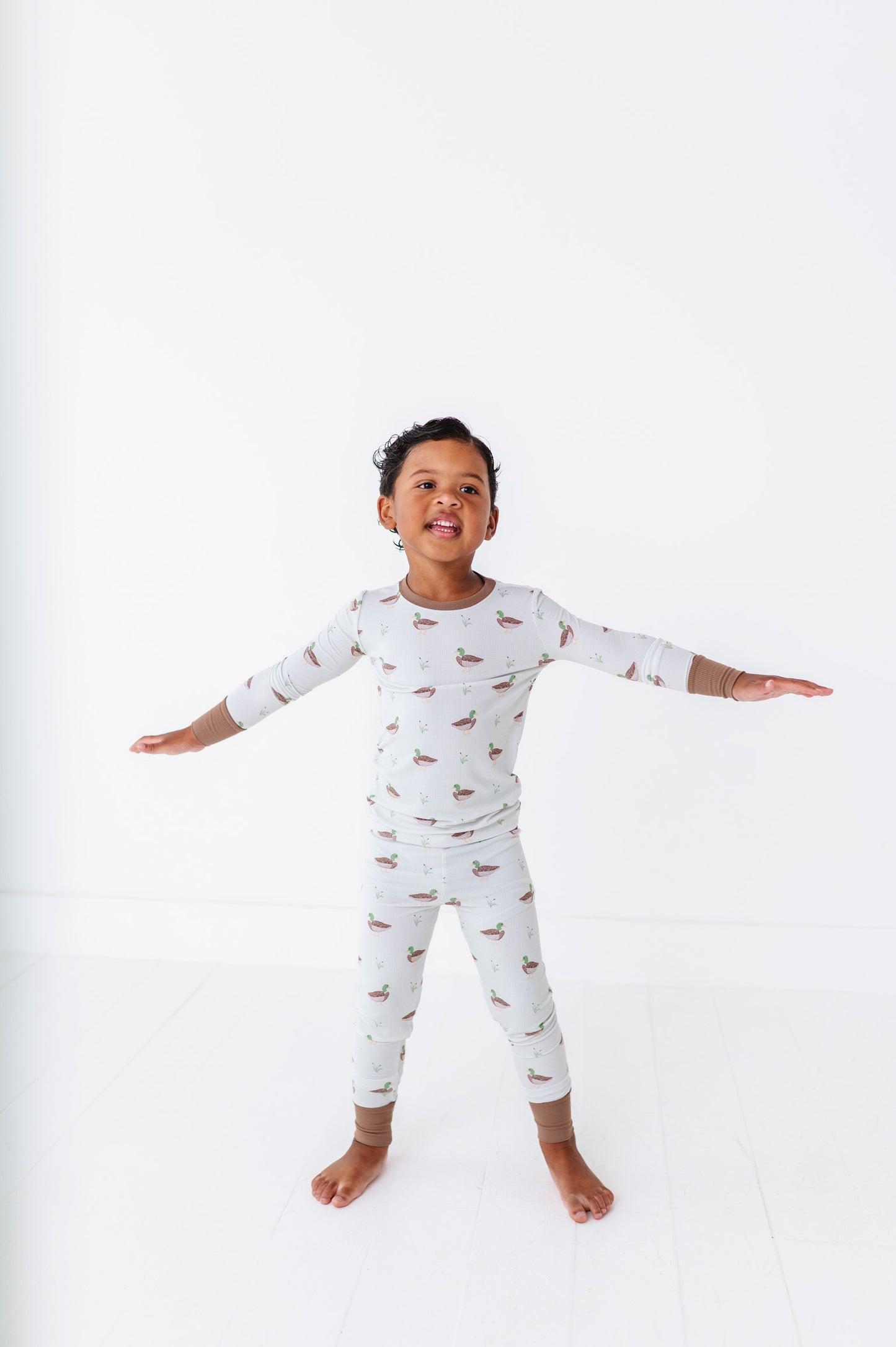 Child wearing a white long-sleeve pajama set with small patterns on a white background
