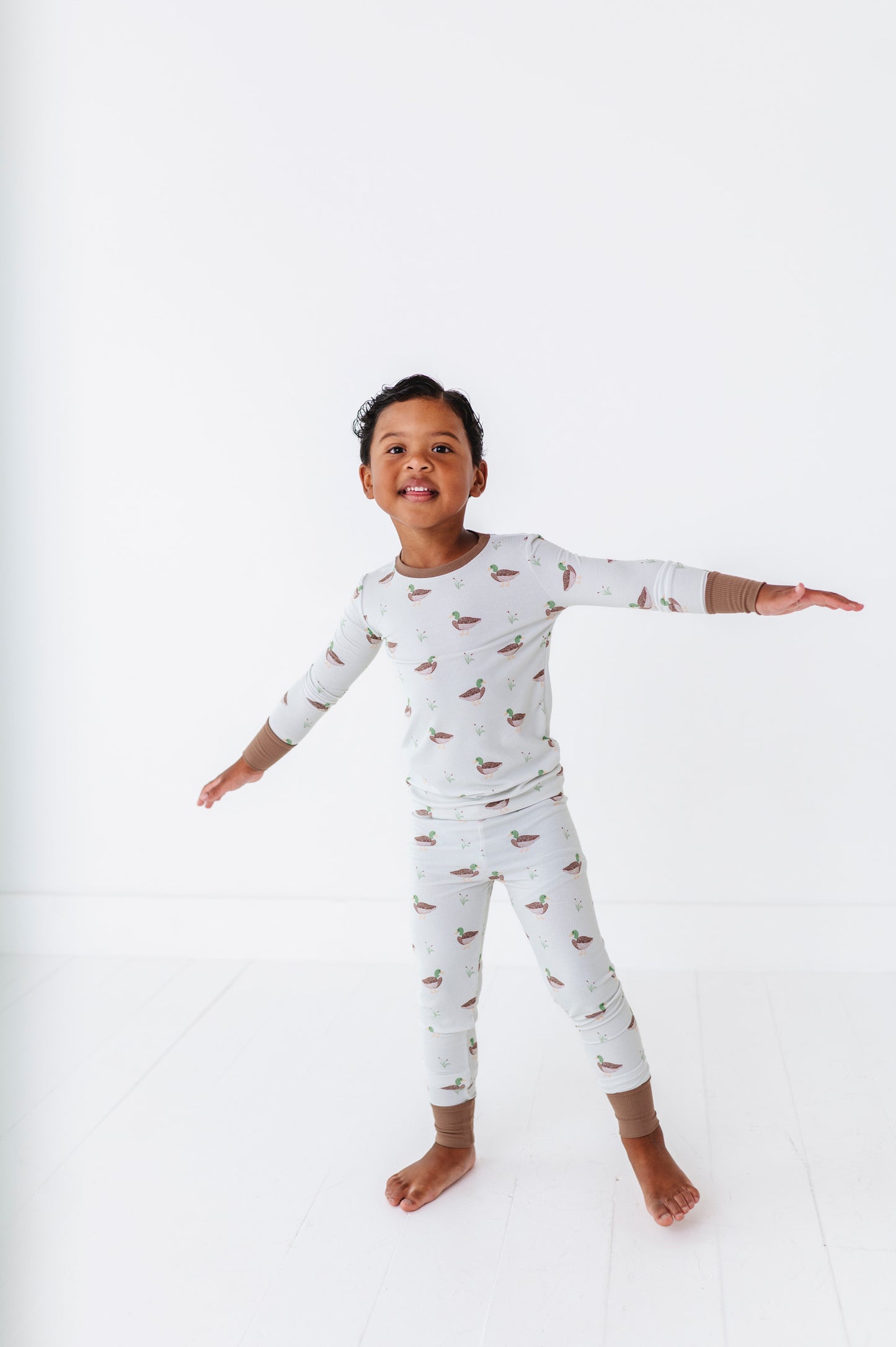 Child wearing a long-sleeve pajama set with animal pattern on a white background