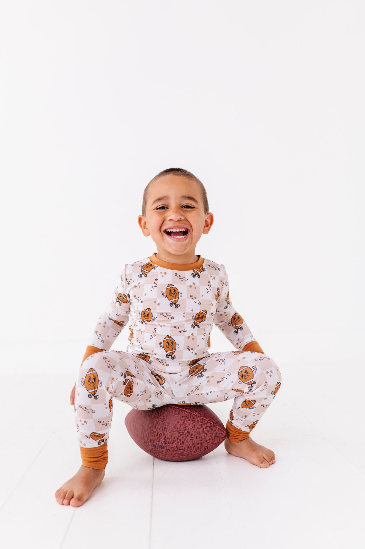 Child wearing a patterned outfit sitting on a ball against a white background
