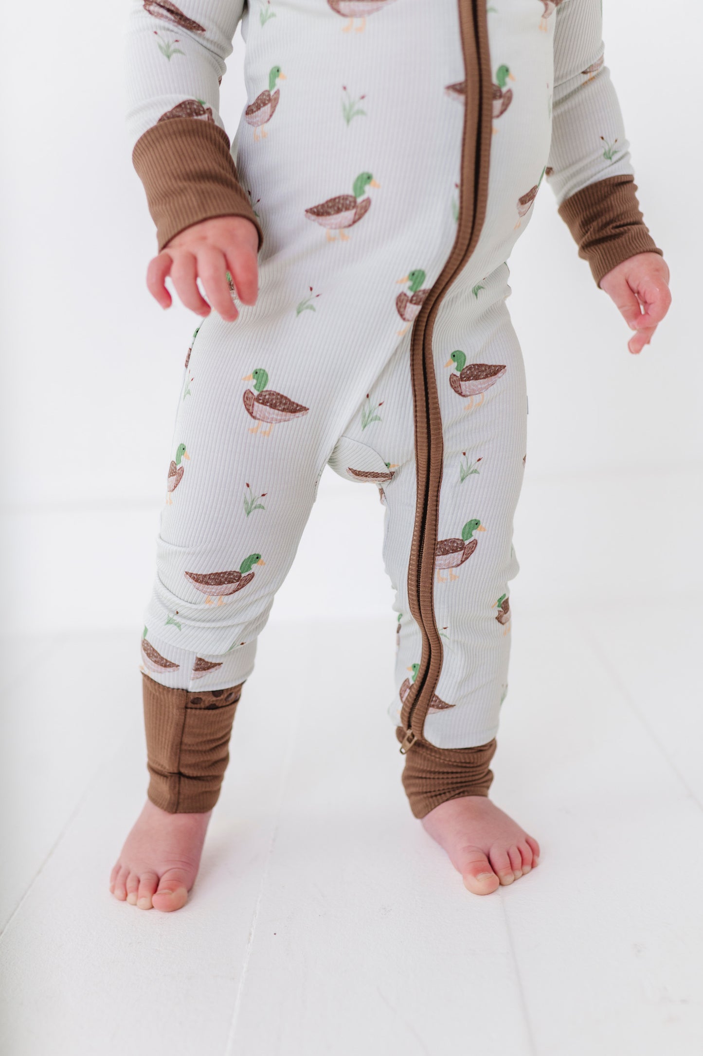 Baby wearing a onesie with duck pattern on a white background
