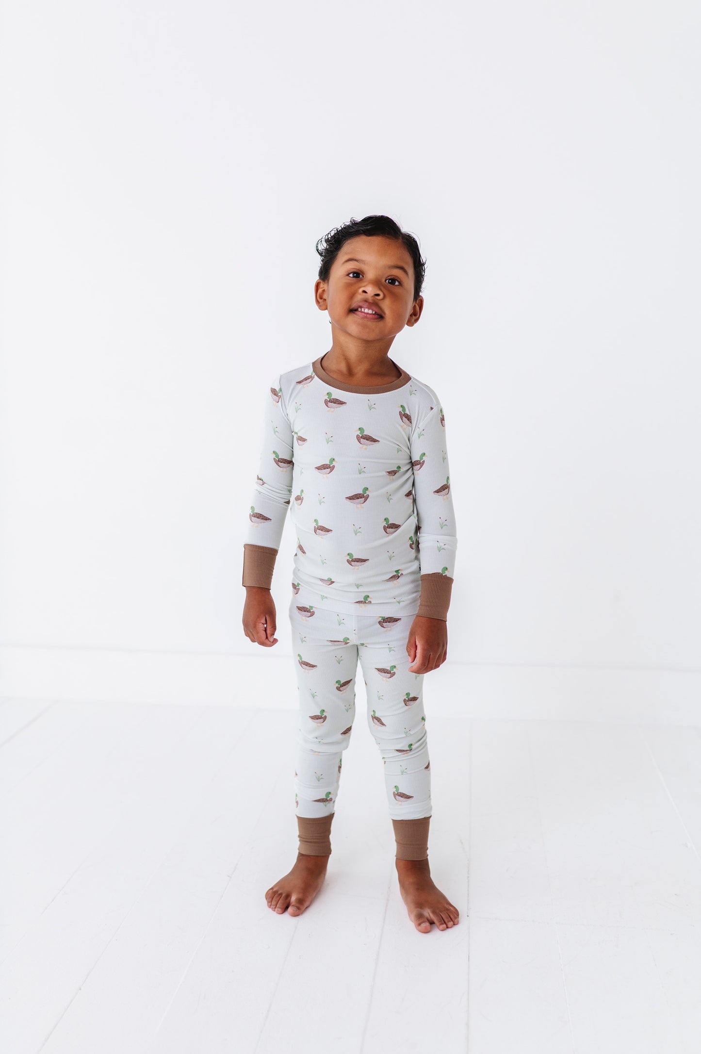 Child wearing a white long-sleeve shirt and pants with small prints on a white background