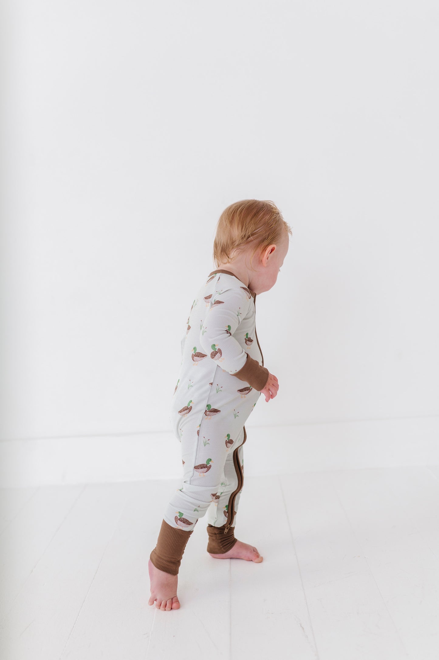 Child wearing a patterned onesie on a white background