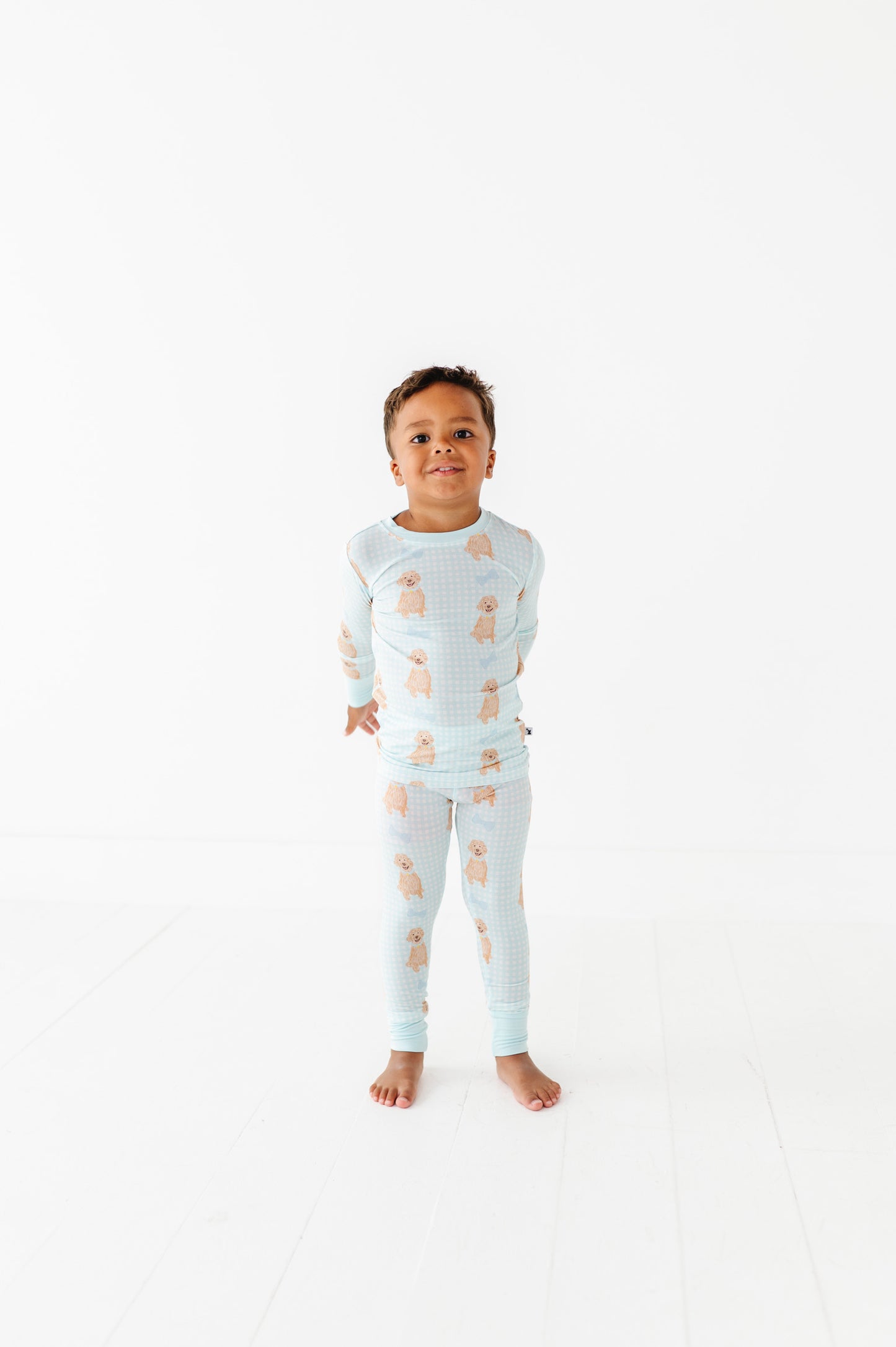 Child wearing a light blue pajama set with bear pattern on a white background