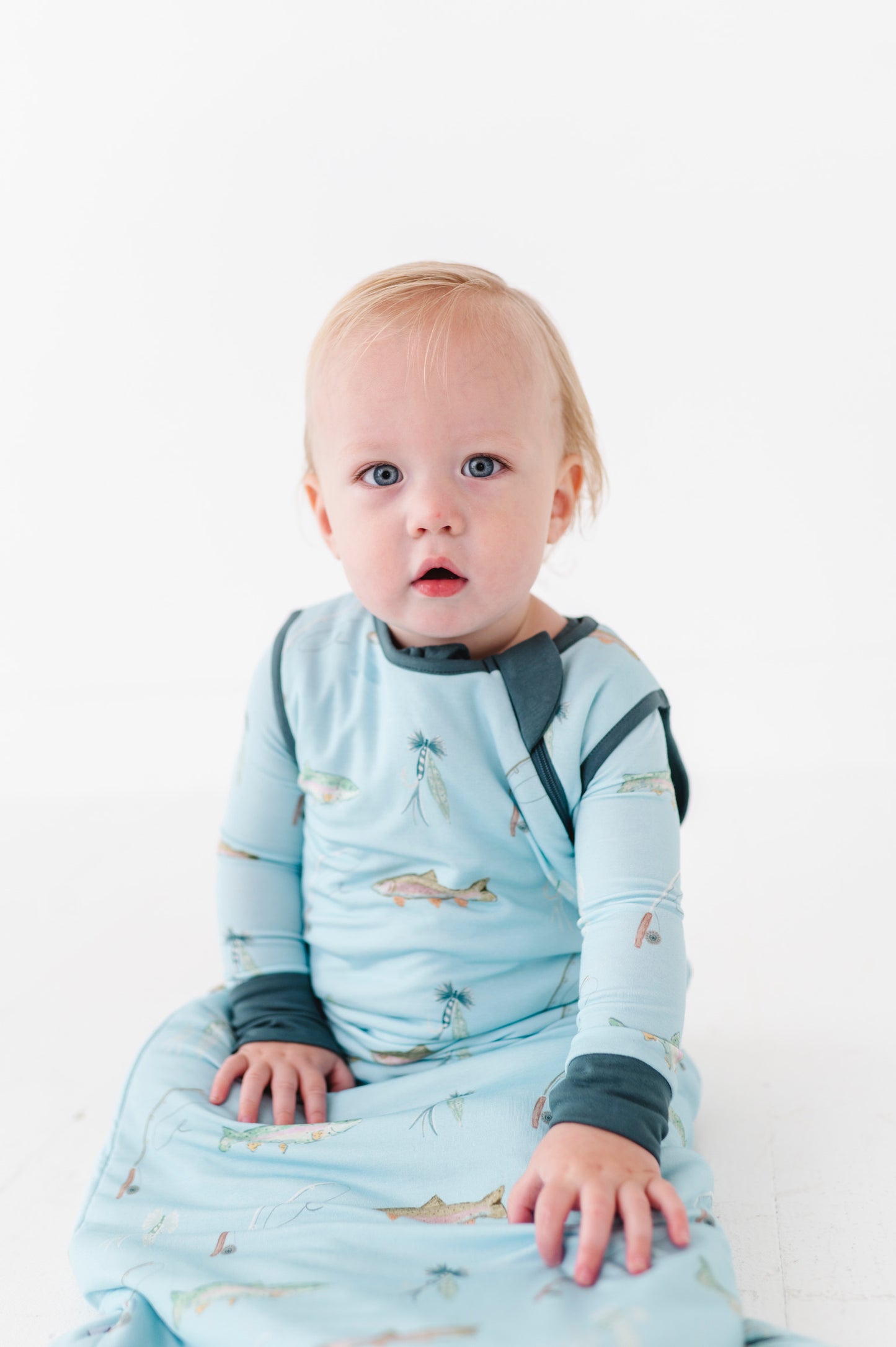 Baby wrapped in a blue sleep sack on a white background
