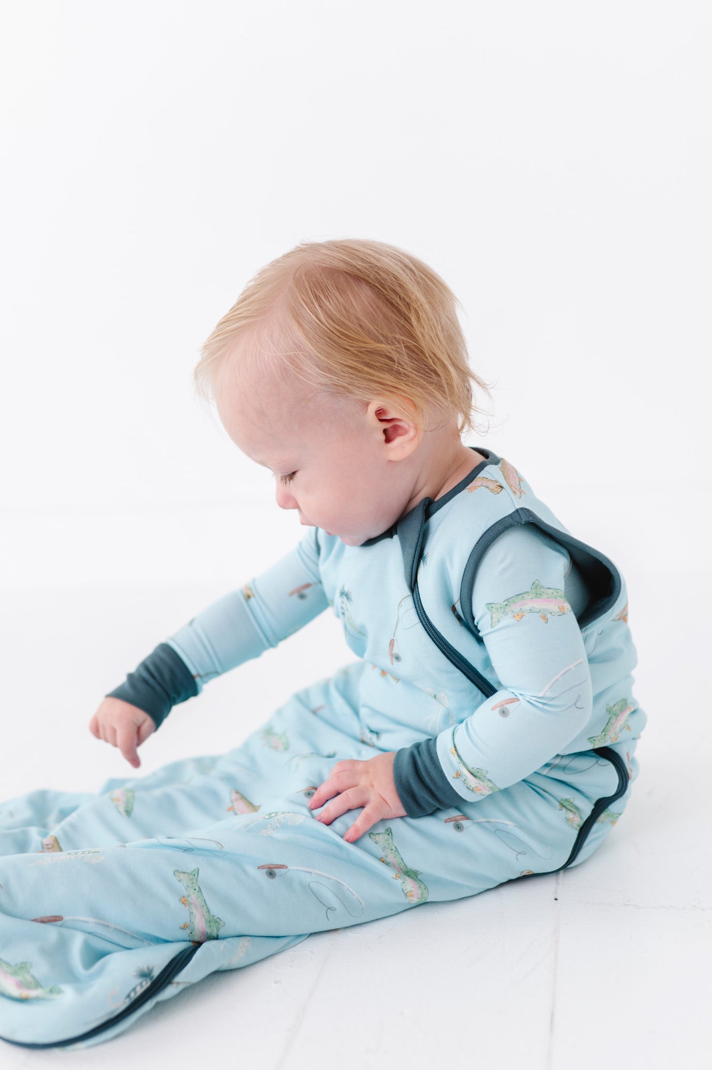 Baby in a blue sleep bag with animal pattern on a white background