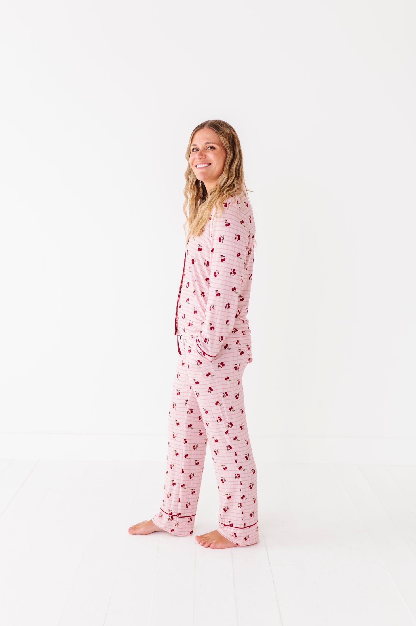 Woman wearing pink pajamas with a cherry pattern on a white background