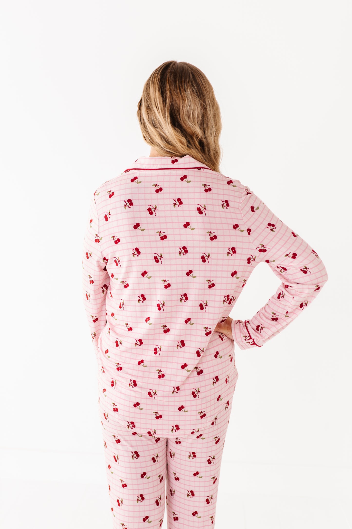 Person wearing pink pajamas with red cherry pattern on a white background