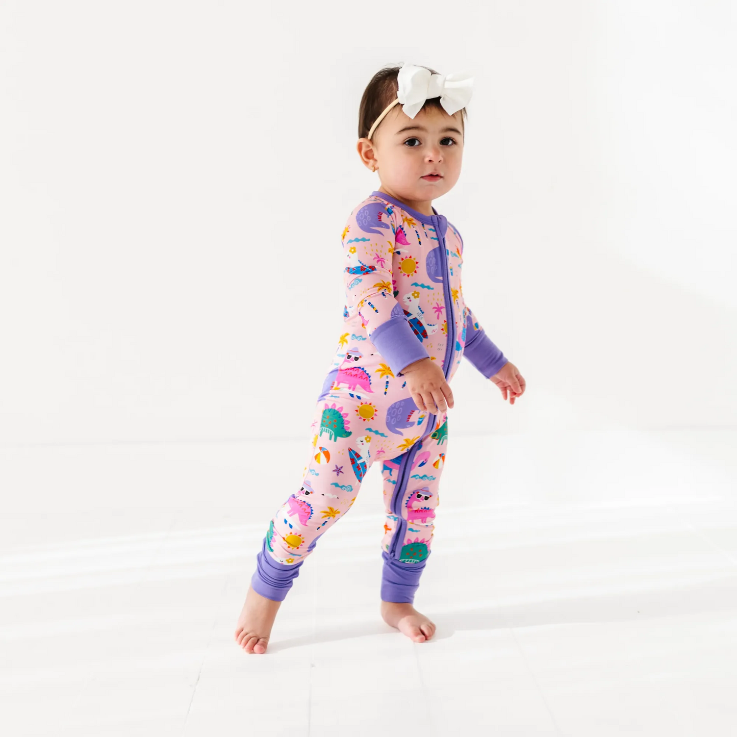 Baby Girl in dinosaur pajamas by Kiki and Lulu