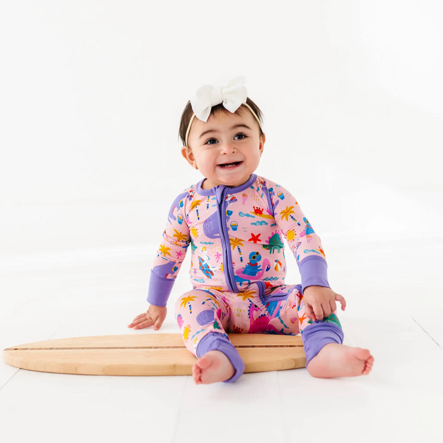 Baby Girl in dinosaur pajamas by Kiki and Lulu