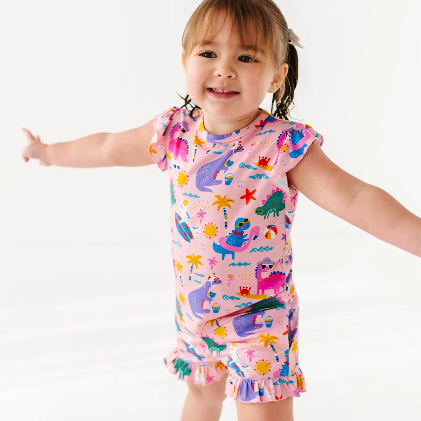 Girl in short pajama dinosaur set by Kiki and Lulu