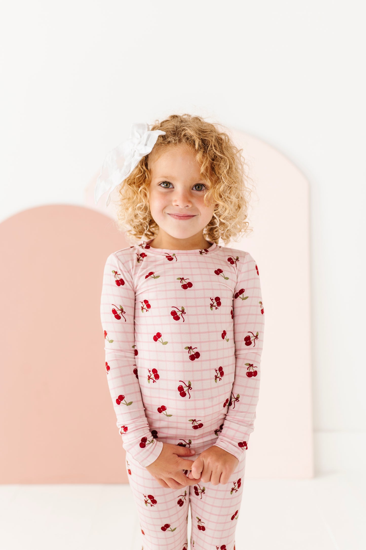 Child wearing a pajama set with cherry pattern on a white background