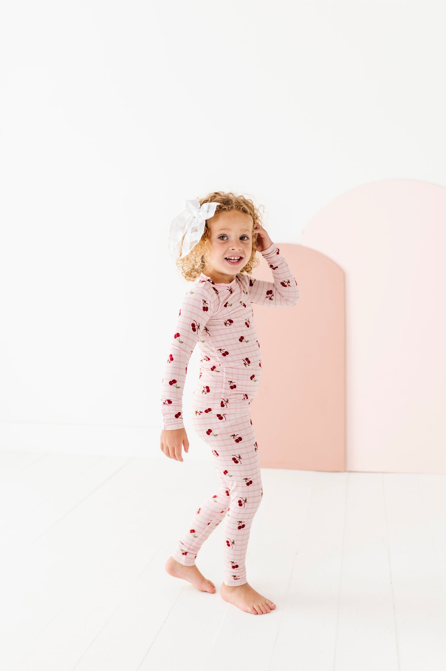Child wearing a cherry-patterned onesie on a white background