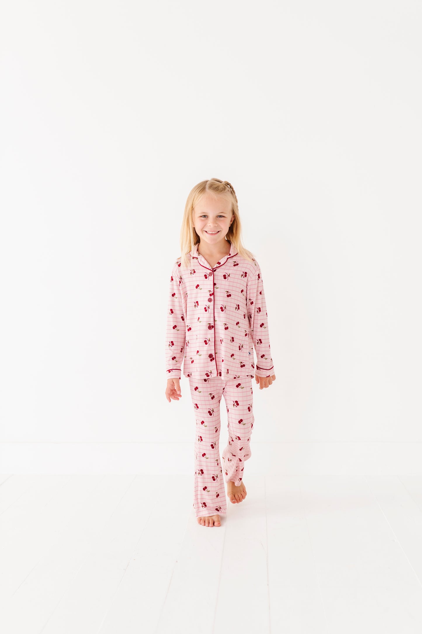 Young girl wearing a pink onesie with a pattern on a white background