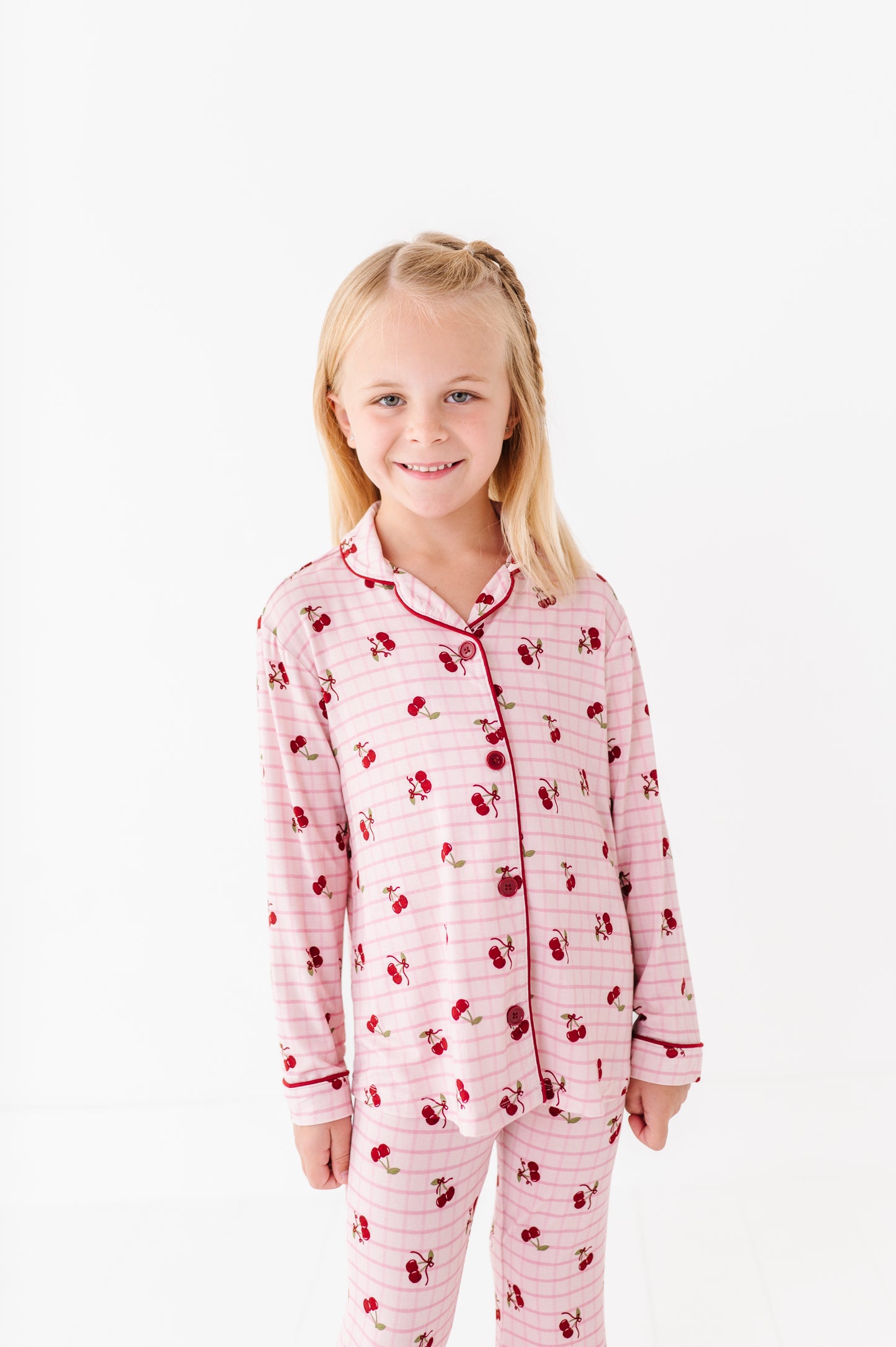Young girl wearing pink pajamas with cherry pattern on a white background