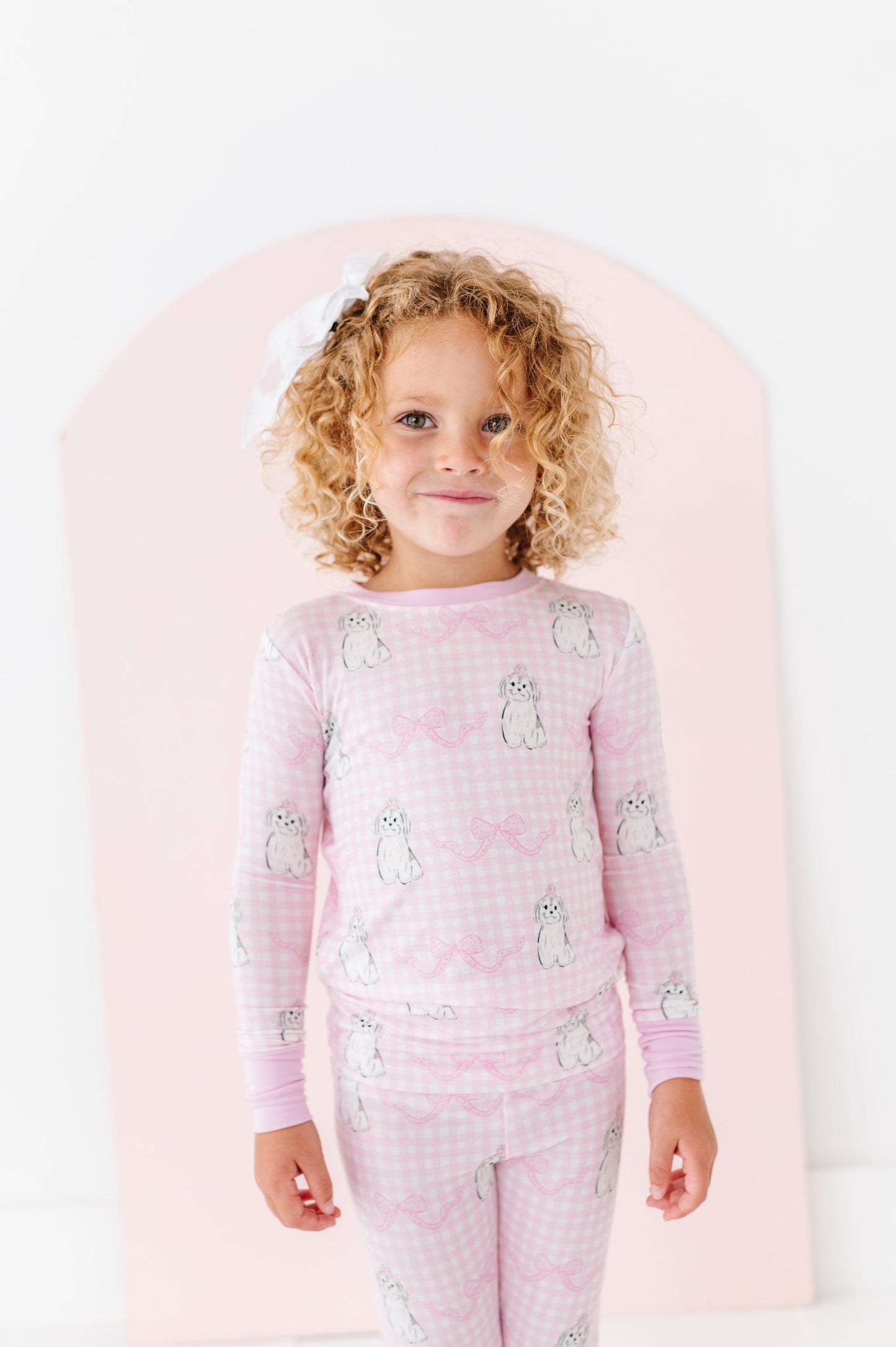 Child wearing pink pajamas with animal pattern on a white background