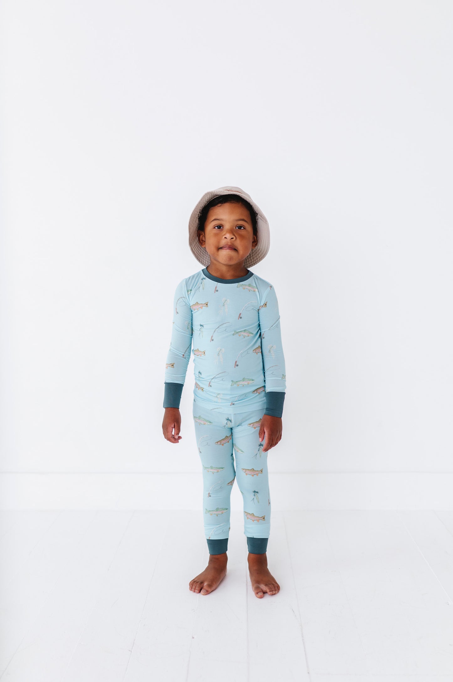 Child wearing a light blue onesie with fish pattern on a white background