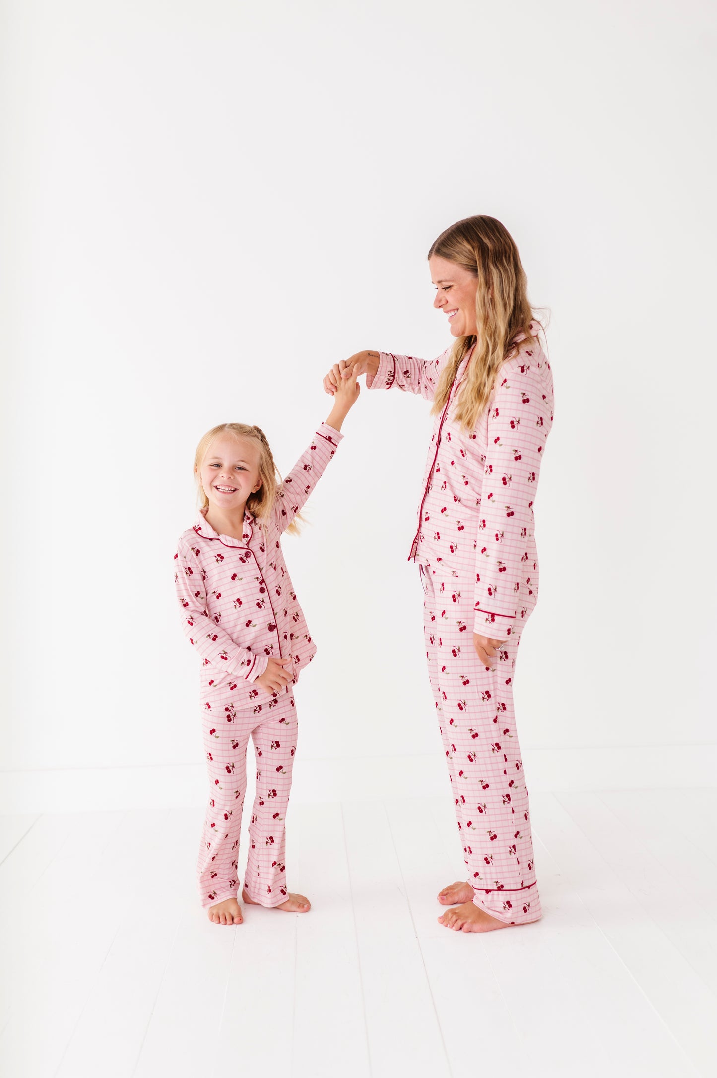 Mother and daughter wearing matching pink pajamas with a heart pattern on a white background