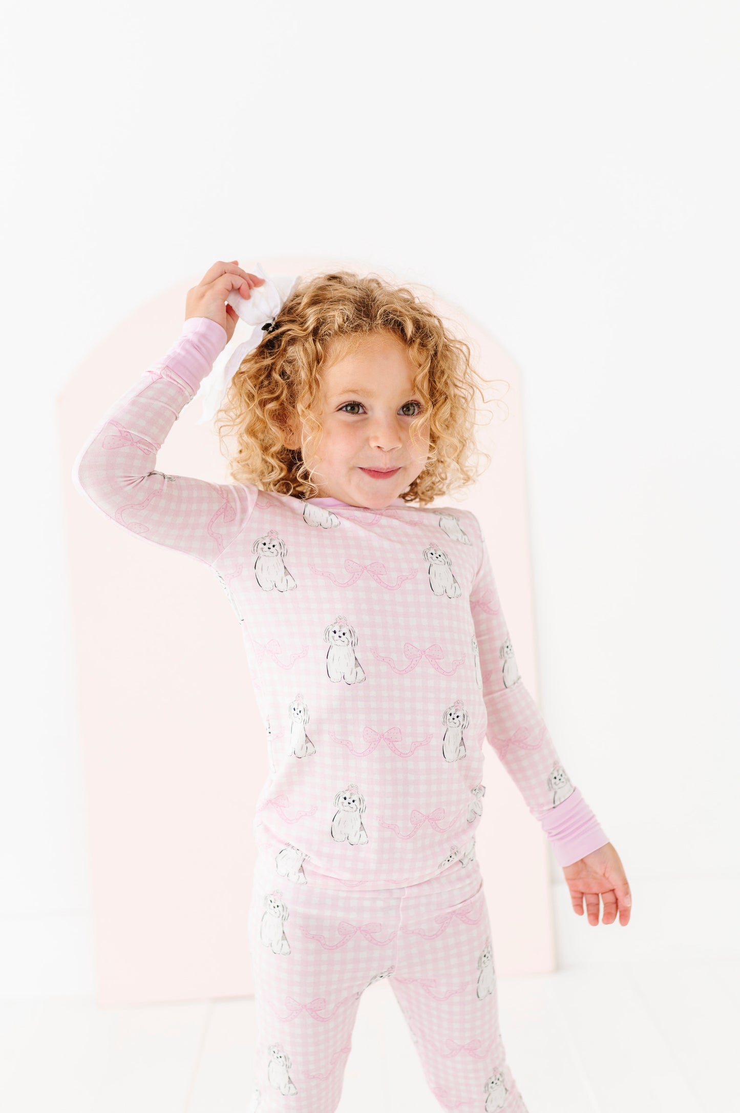 Child wearing pink pajamas with animal prints on a white background