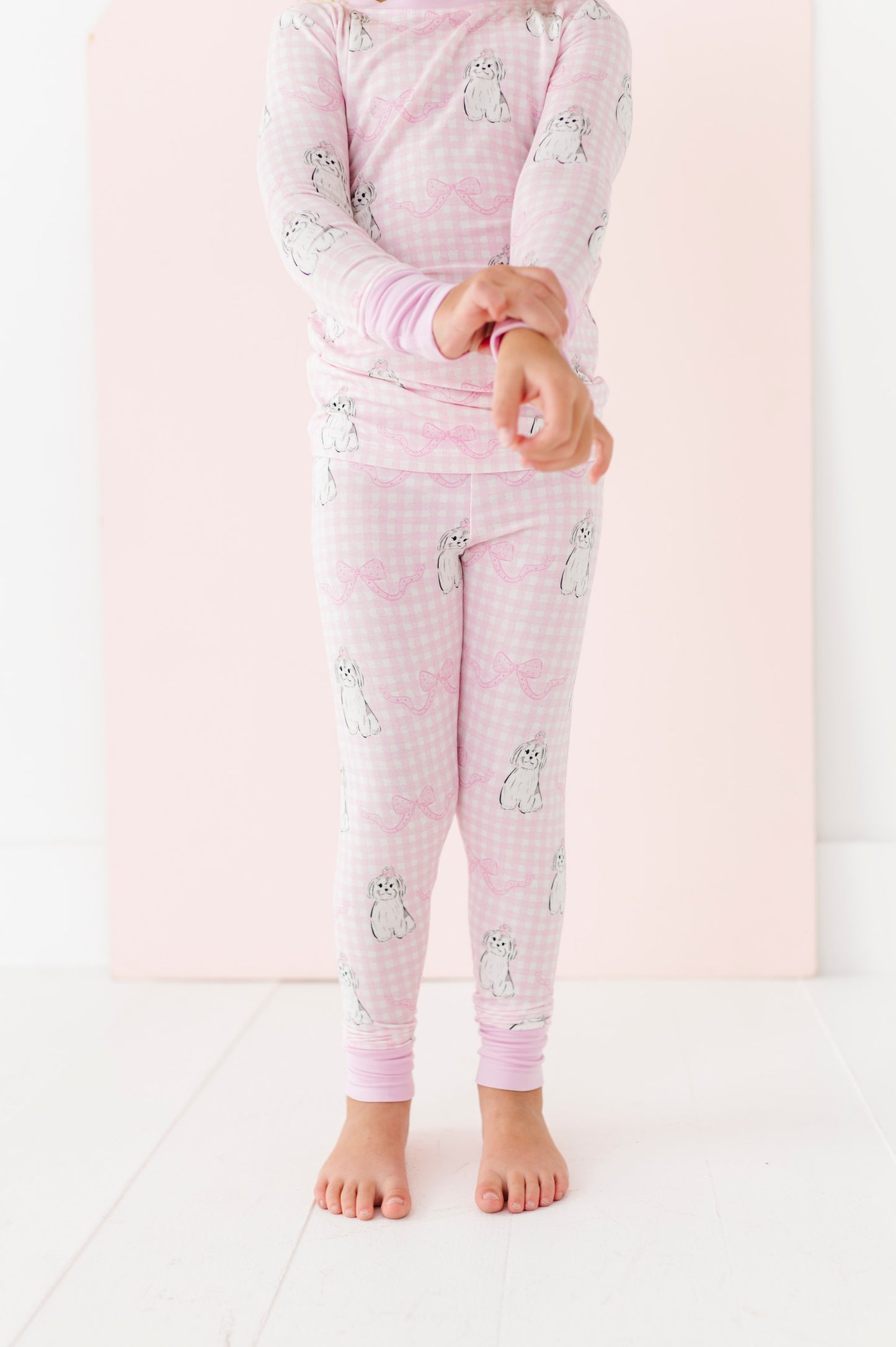Child wearing pink pajamas with animal prints on a white background
