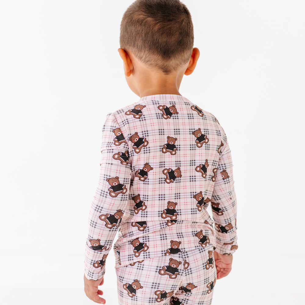 
                      
                        Child wearing a checkered pajama set with teddy bear pattern on a white background
                      
                    