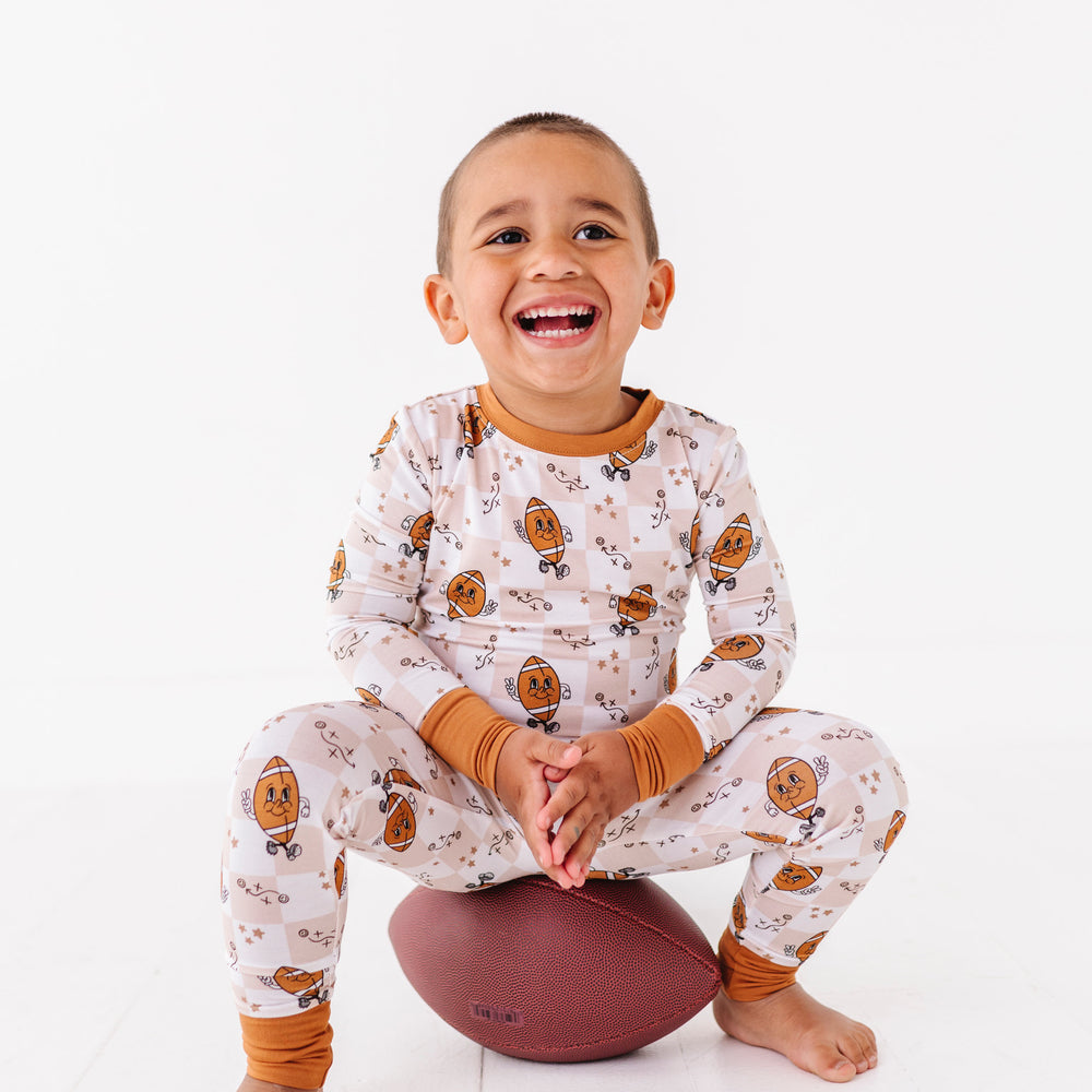 
                      
                        Child wearing patterned pajamas sitting on a white floor with a white background
                      
                    
