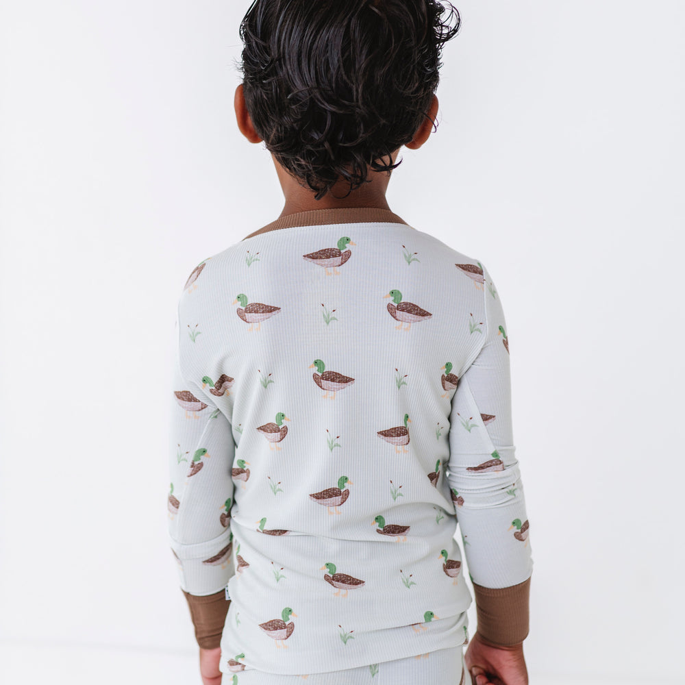 
                      
                        Child wearing a long-sleeve shirt and pants with duck pattern on a white background
                      
                    