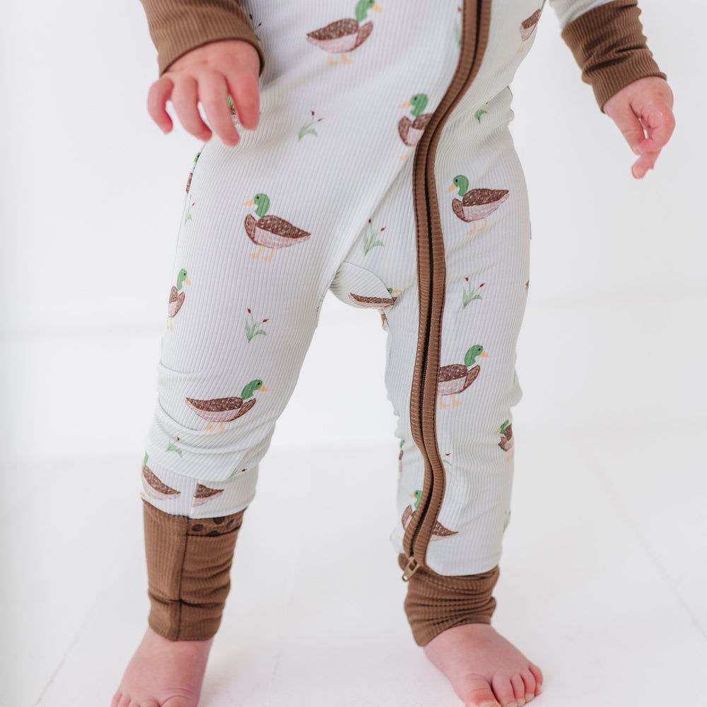 
                      
                        Baby wearing a onesie with duck pattern on a white background
                      
                    